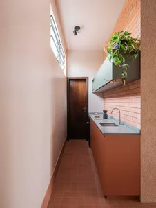Small kitchen with a brown cabinet, sink, and potted plant, featuring natural light from a window above the sink