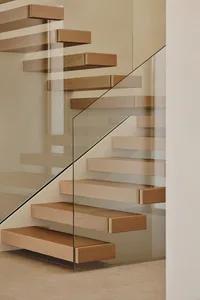 A wooden staircase with a glass railing in a bright and airy room with a white wall, creating an elegant and sophisticated atmosphere