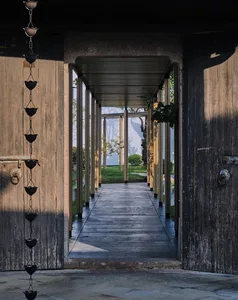 A modern doorway with a wooden frame and glass door, open to a bright and airy hallway with glass panels, in a residential setting with natural light and warm ambiance