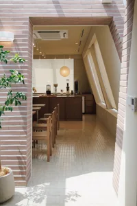 Dining area with wooden tables, chairs, and tableware, lit by natural light and warm ambiance