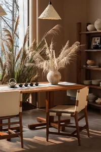 A well-lit dining room with a wooden table and chairs, surrounded by potted plants and a modern, minimalist aesthetic