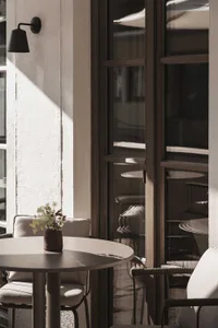 A modern dining space with a wooden table and metal chairs, surrounded by a window with natural light, creating a warm and inviting atmosphere
