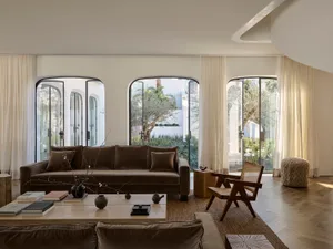 Cozy modern living space with brown furniture, potted plants, and natural light from windows
