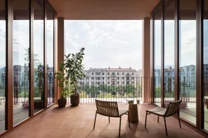 Comfortable modern living room with a large window, a couch, a chair, and potted plants, well-lit by natural light