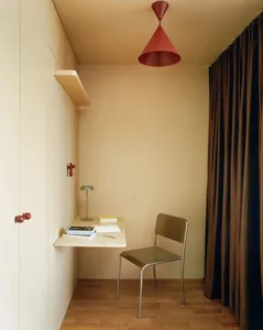 A small, dimly lit room with a brown chair and table, and a red light hanging from the ceiling