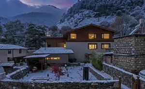 A rustic wood house surrounded by a snow-covered forest, with a serene and peaceful atmosphere