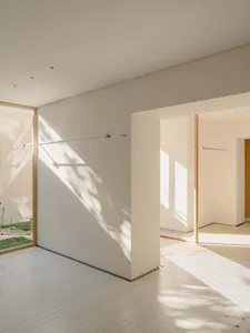 Bathroom with a white wall, a doorway, a shower, and a towel rack, lit by natural sunlight