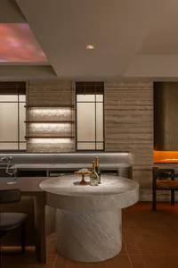 A dimly lit bar with a marble countertop, a wine bottle, and a wine glass, set in a modern restaurant or bar space