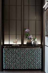 Warm and inviting room with a wooden cabinet, a vase of flowers, and natural light from a window