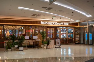 A modern cafe with a warm atmosphere, featuring wood and glass elements, soft lighting, and various furniture arranged in different areas