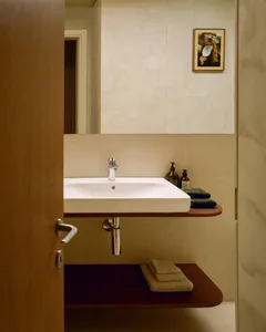 Modern bathroom with a white sink, brown tile floor, and a towel rack on the right side, under dim lighting
