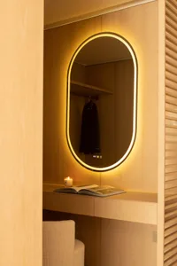 A simple bedroom with a wooden floor and a large mirror on the wall, reflecting the room's interior and creating a sense of depth and space