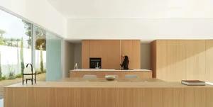 Modern kitchen with wooden cabinets, a white countertop, and natural light from a window