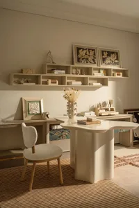 A modern living room with a white table, chair, and bookshelf, surrounded by books and a vase with flowers, in a clean and minimalist design with predominantly white colors and wood accents