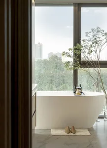 Bathroom with a white bathtub, a window, and a potted plant, creating a calm and inviting atmosphere
