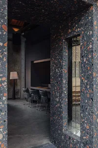 Cozy modern dining space with a black wall, stone-like patterned wall, a dining table, and chairs, featuring a TV mounted on the wall