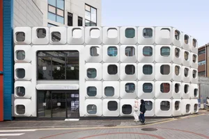 A modern building with a white facade and grid-like windows, set against a bright and sunny day