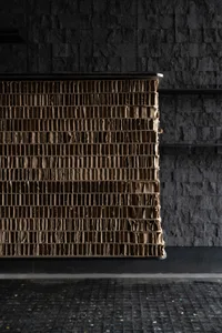 A dark room with a wall made of stacked cardboard boxes, creating a moody atmosphere with dim lighting