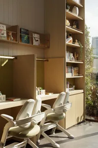 A home office with a wooden desk and two white chairs, surrounded by natural light from a window, creating a cozy and inviting atmosphere