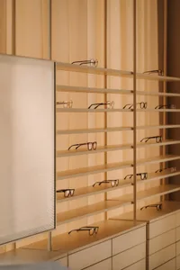 A wooden shelf displays a diverse selection of glasses in various shapes and sizes in a store or display area