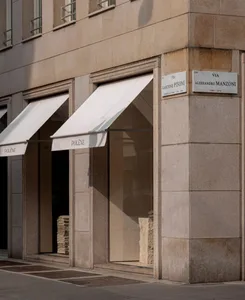 A classic building with a stone facade and a large storefront featuring a white curtain, open to reveal the interior