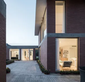 A modern brick building with a large glass window, situated in a well-lit area with natural light