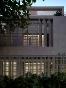 Photograph of a modern building with a concrete exterior, large window, and natural light