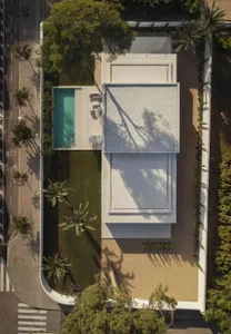 A modern house with a concrete exterior, a pool, and a patio with chairs, surrounded by natural light and a relaxed atmosphere
