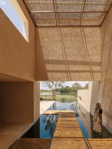 A modern building with a wooden deck and pool, surrounded by natural sunlight and a relaxing atmosphere