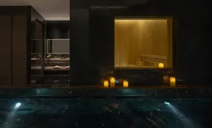 Dimly lit modern bathroom with a large window, black bathtub, sink, and toilet, creating a moody atmosphere