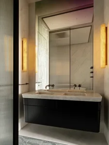 A modern bathroom with a sink, mirror, and bathtub in a dimly lit space