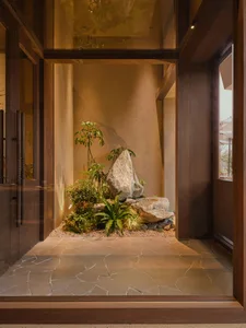 Cozy living space with a stone floor, rock wall, and potted plant, featuring dim lighting and natural elements