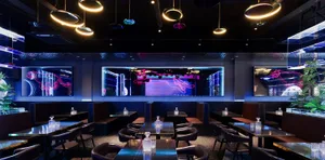 Elegant restaurant interior with black and purple decor, wine glasses, and dim lighting