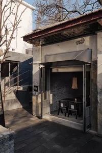 Dimly lit dining space with a wooden table and chairs, surrounded by a doorway and metal fixtures, in a warm and inviting atmosphere