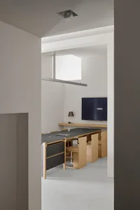 Cozy dining area with a wooden table and chairs, a TV on the wall, and dim lighting