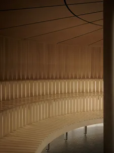 A wooden bench in a dimly lit room, possibly a lobby or hallway, with a traditional or classic style