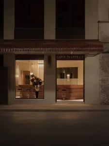 一間店面外觀，牌子寫著 　　 Love Isabelle，前面放置了幾個花盆和椅子，背後是一個大窗口，充滿溫暖和邀人的氛圍