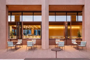A dimly lit restaurant with a brown and white color scheme, featuring multiple tables and chairs, and a cozy atmosphere