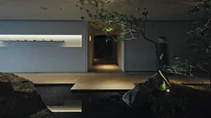Cozy modern living room with a bonsai tree, stone floor, sink, and mirror, lit by dim lighting