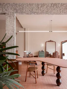 Modern hair salon with a large mirror, wooden table, and chairs, well-lit and inviting