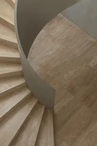 A curved stone staircase with visible steps, set in a building with natural light from above, creating a bright and inviting atmosphere