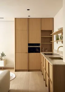 Well-lit kitchen with wooden cabinets, a black oven, and a sink, featuring a modern and functional design with natural materials