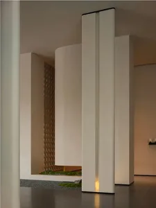A large, open room with a white color scheme, white pillars, and a small garden area with a potted plant, creating a clean and minimalistic atmosphere