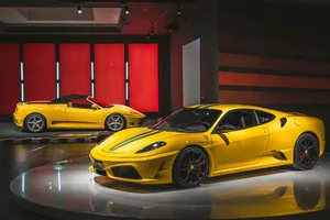 Two yellow sports cars on display in a modern showroom with a red wall and sleek atmosphere