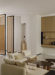 A modern living room with a couch, chair, and TV, featuring white furniture and natural light from the windows