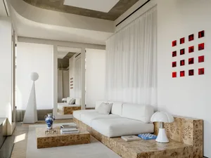 A well-lit living room with a white couch, coffee table, chair, and lamp, creating a comfortable and inviting atmosphere