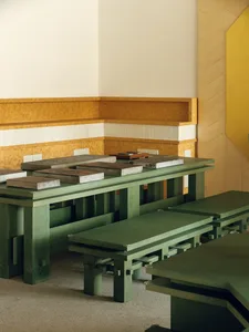A modern dining space with a wooden table surrounded by metal benches, well-lit and inviting