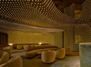 A large, well-lit room with a high ceiling, featuring couches, chairs, and dining tables, arranged in a contemporary and sophisticated style for comfort and functionality