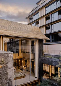 A modern building with a glass wall extending from the ground floor to the top floor, allowing natural light to enter and creating a spacious atmosphere