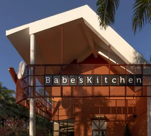 A casual restaurant with a modern architectural style, featuring a red roof, orange and white colors, and a dining table and chairs in a warm and inviting space with natural light
